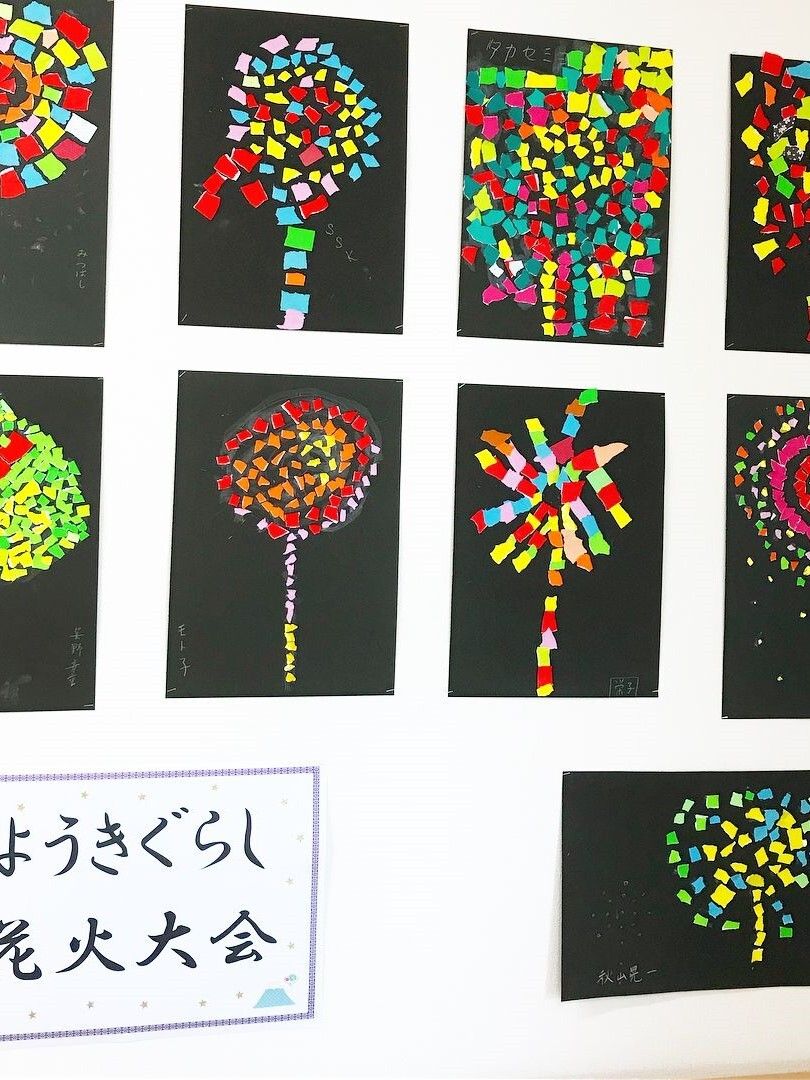 黒の台紙に華やかな色の折り紙を貼り付け、花火を表現した作品が飾られている。