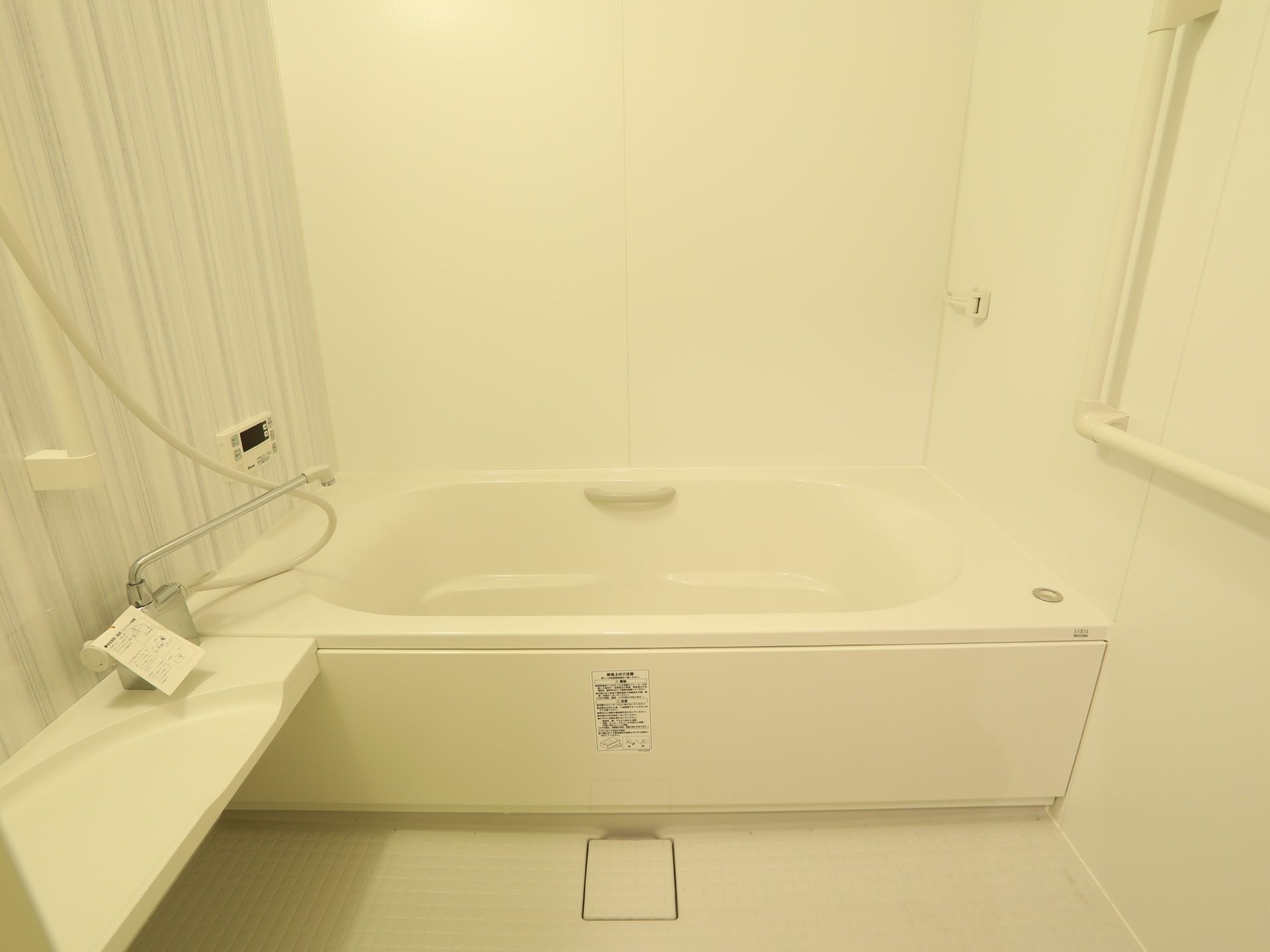 白い内装のきれいなユニットバスである。壁には手すりが設置されており、床は滑りにくいような素材になっている。