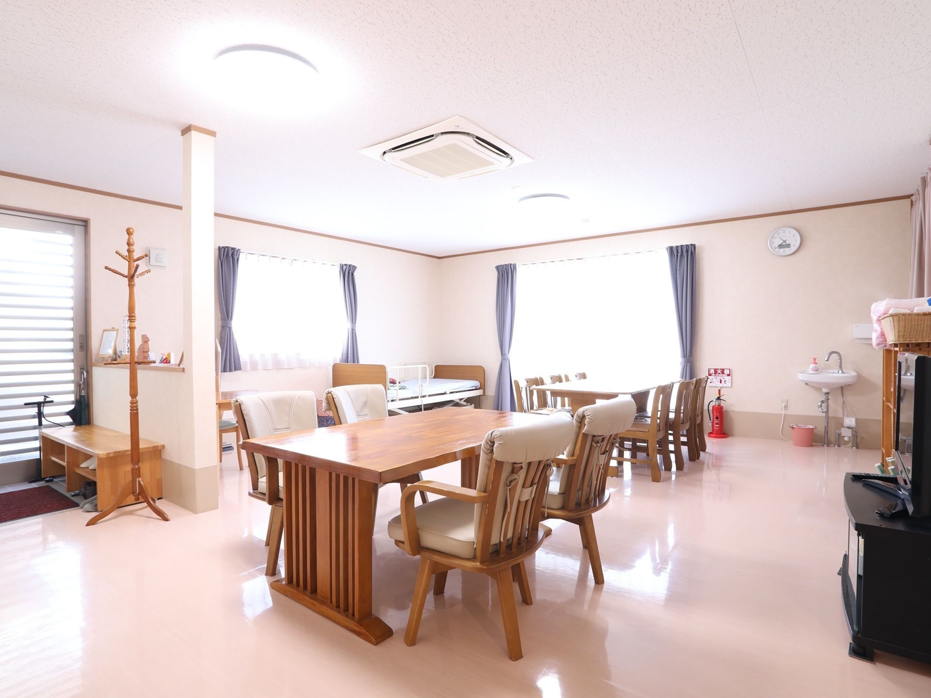 明るい食堂には掃き出し窓と腰高窓がある。ダイニングテーブルと椅子がセットされており、奥には洗面台が設置されている。