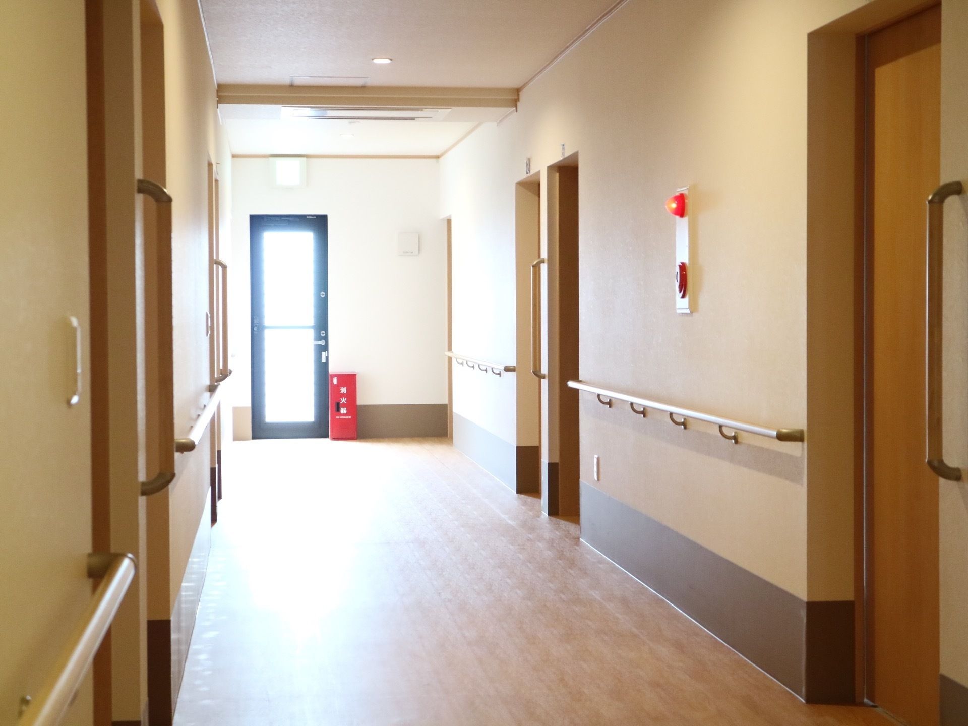 廊下は車椅子をご利用の方でも問題のない広さがある。左右の壁には横方向だけではなく縦向きにも手すりが付いている。