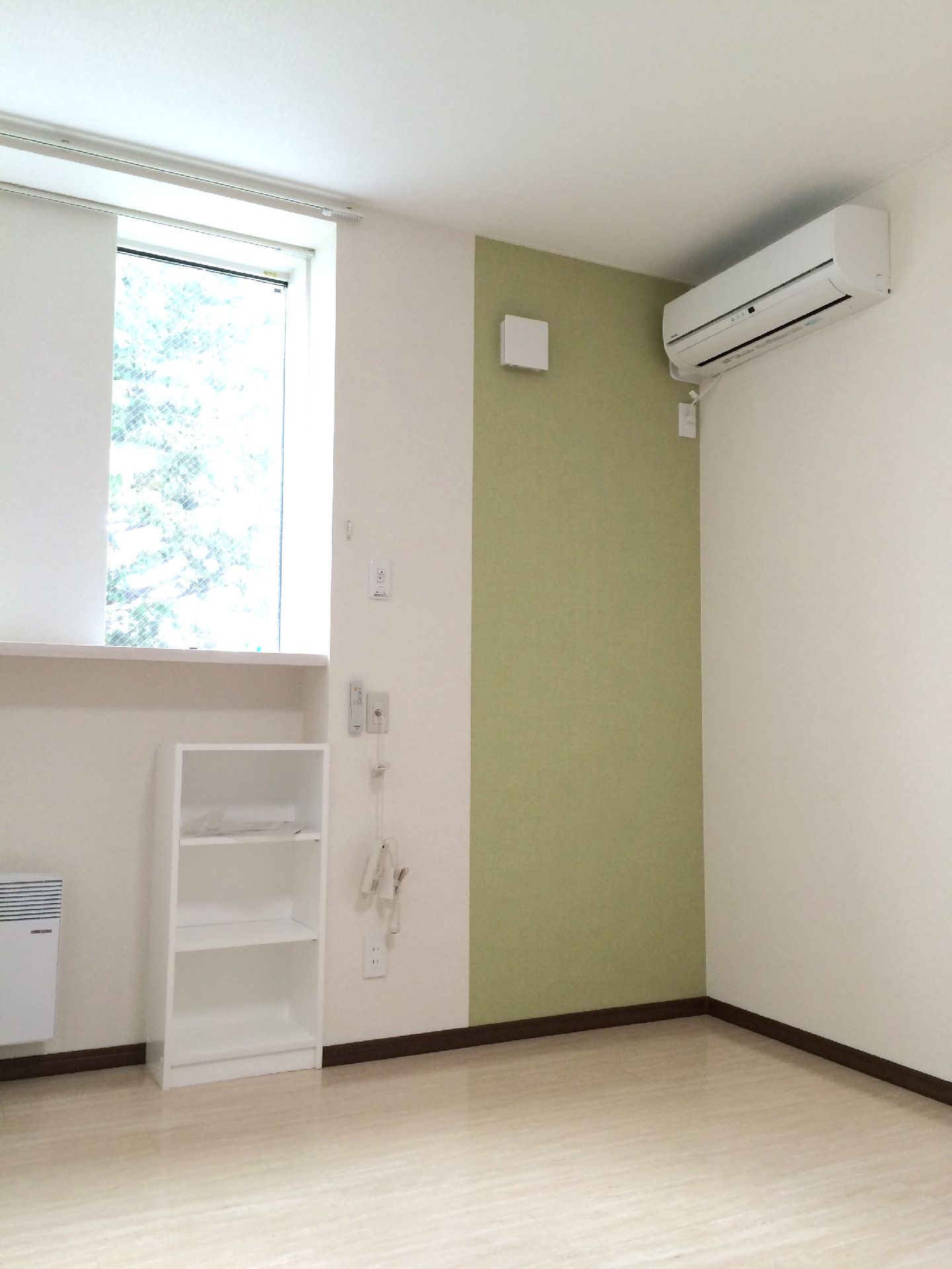 エアコン付きのフローリングの部屋には大きな窓もあり、明るい雰囲気。壁には花のイラストやアクセントクロスも貼られている。