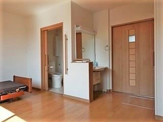 ワンルームタイプの部屋の設備写真。トイレと洗面台があり、奥のほうにベッドがある