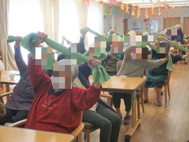 ダイニングテーブルが並べられたスペースで、椅子に座りカラオケを楽しむ入居者様