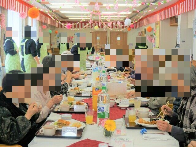 機能訓練用の基部に座って足を動かしている高齢者の様子。施設内の一角で写した写真