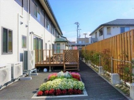 小さな花壇と中庭が写っている施設の写真。左側に居住スペースがある建物