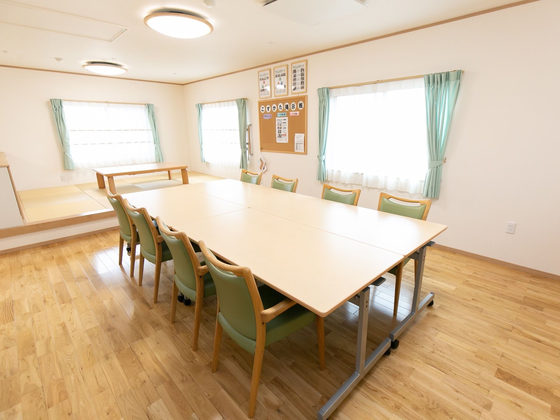 真ん中に大きなテーブルといくつもの椅子が置かれた談話室。奥の一段高い所には畳敷きのスペースが設けられている。