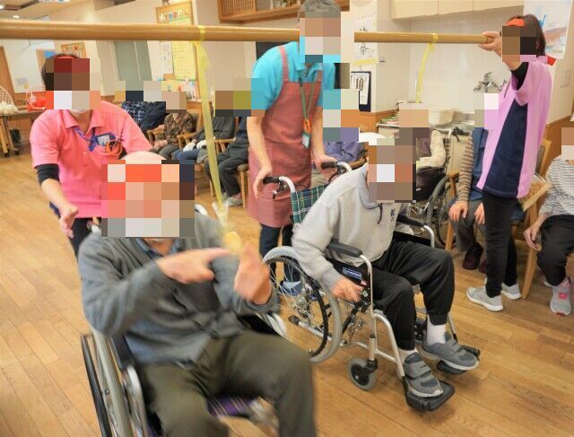 孫と一緒に記念写真を撮る高齢者と娘・孫。広い公園のようなスペース