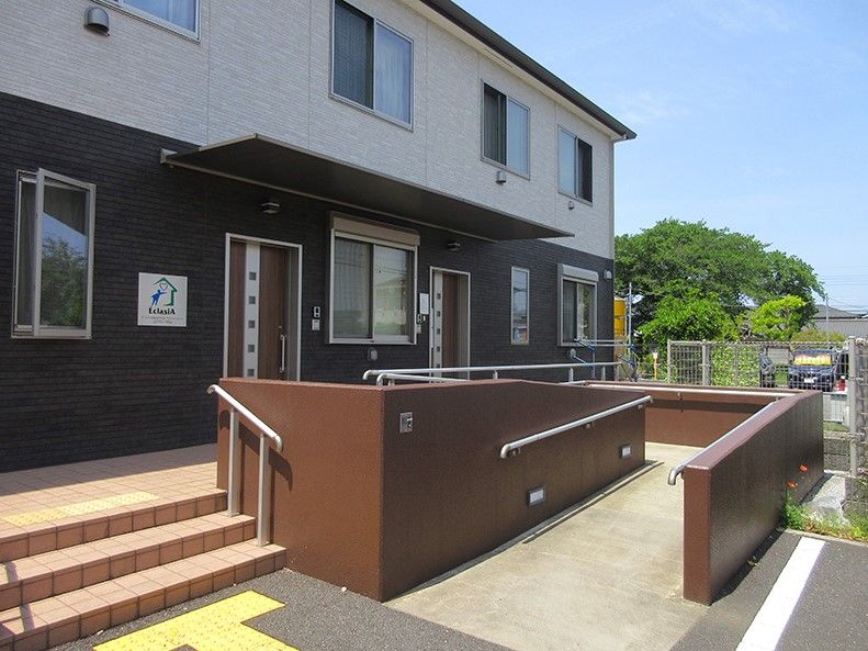入り口に階段とスロープがあるツートンカラーの外壁の2階建て建築物