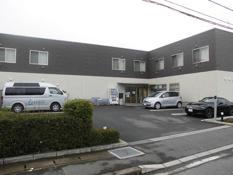 敷地内に自動販売機やベンチがある、2階建て建築物