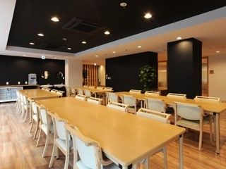 黒い壁紙がおしゃれなカフェのような雰囲気を作っている食堂。長方形のダイニングテーブルが複数並んでいる。