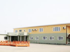 グリーンとイエローの2階建ての建物は横に長く、広い敷地内にはウッドデッキもある。