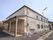 施設は薄茶色のレンガ調の外壁で2階建ての建物。入り口にはスロープがありバリアフリー。室外機や給湯器が設置されているのが見える。