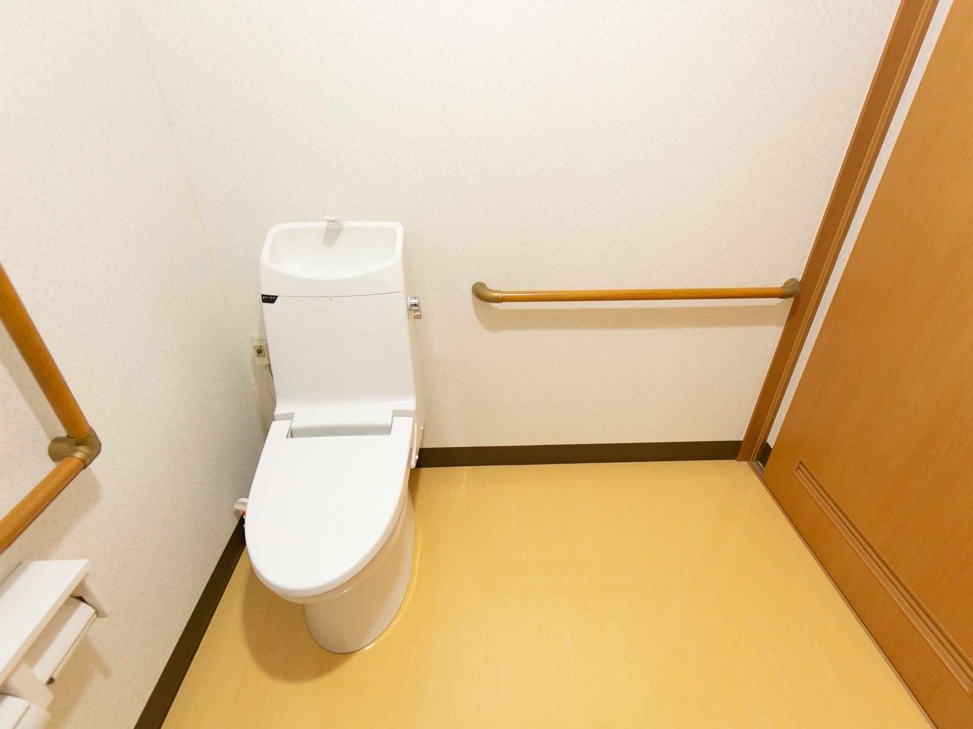 ゆとりあるスペースの清潔感があるトイレになっている。壁には手すりが設置されており、立ち上がる際に体を支えることができる。