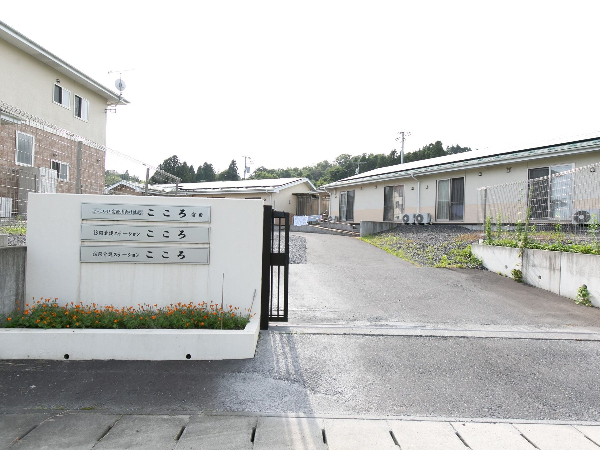 施設は広い敷地の中にあり、しっかりとした門がある。門には施設名のプレートがかかっている。