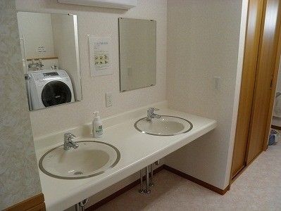 ドラム式の洗濯機が設置された洗面所。奥には収納スペースがあり、二つの洗面所は車いす対応。