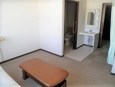 テーブルが置かれたスペースからは洗面所とトイレが見える。グリーンのカーテンもつけられている。