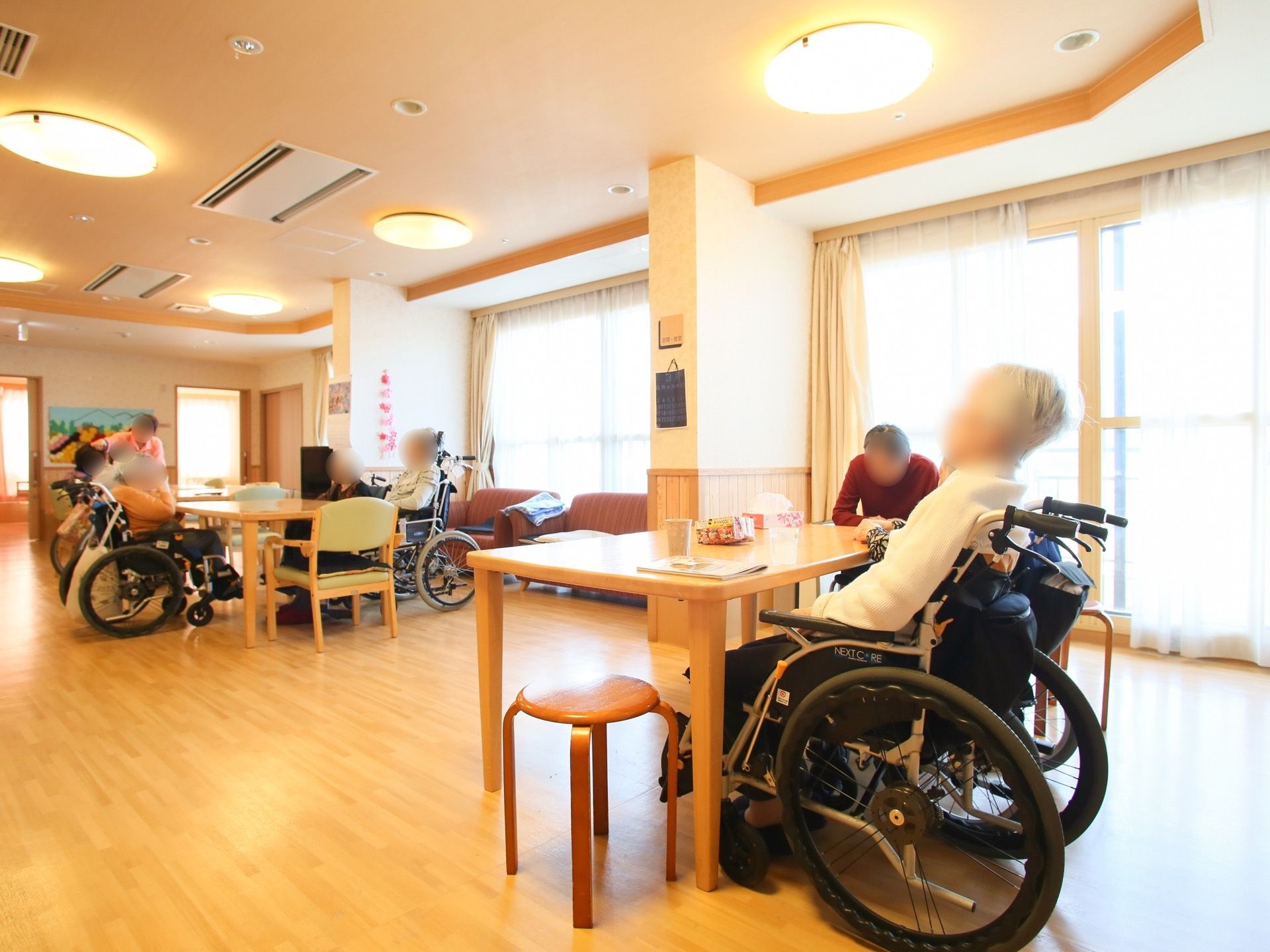 長方形のテーブルが、広い間隔を取って置いてある。肘掛け椅子や丸椅子が近くに用意されている。近くには大きな窓があり、日光がよく入っている。