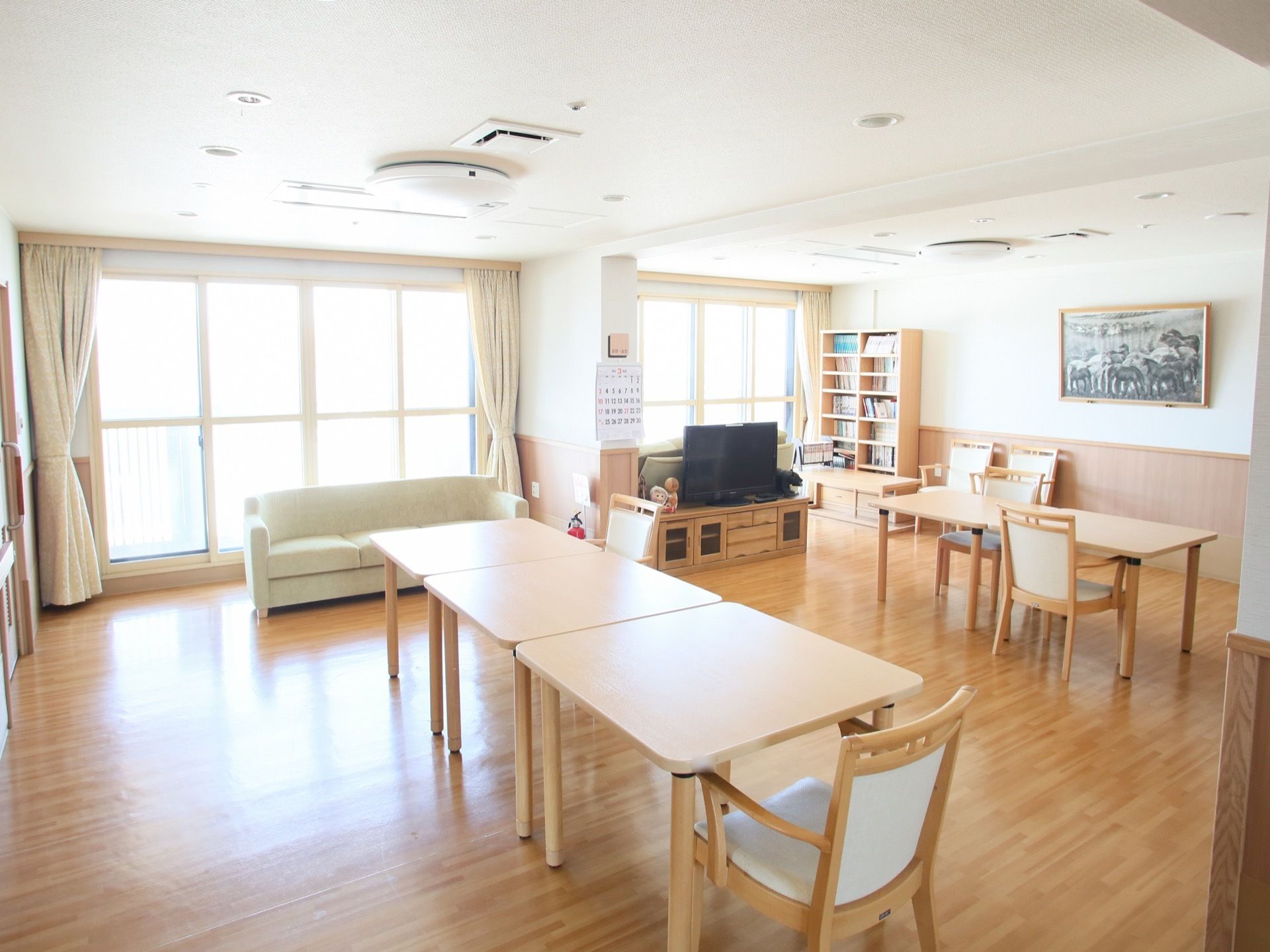 窓から入る日光で、明るく照らされている。テーブルには、肘掛け椅子が置いてある場所以外にも、車椅子の場所が確保されている。