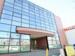 前面部分が一面ガラス張りになっている大きな建物がある。玄関部分にはルーフが付いており、地面は緩くスロープになっている。