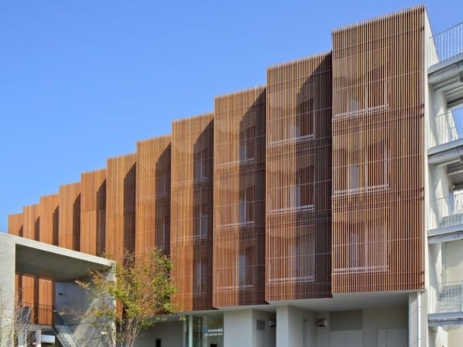 ブラウンと白の4階建ての建物。センスを開きかけたような形状をしている。