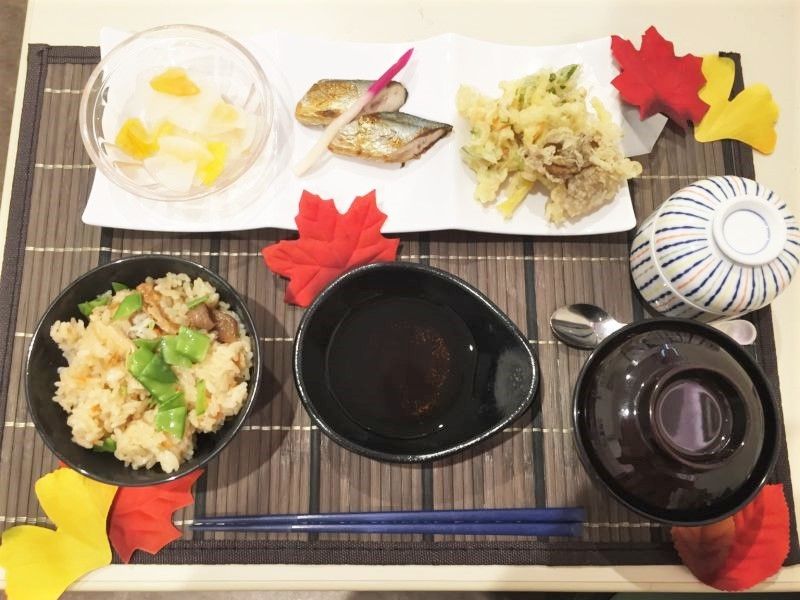 アジアンテイストのランチョンマットの上には炊き込みご飯や汁物、茶わん蒸し、天ぷらや焼き魚がある。
