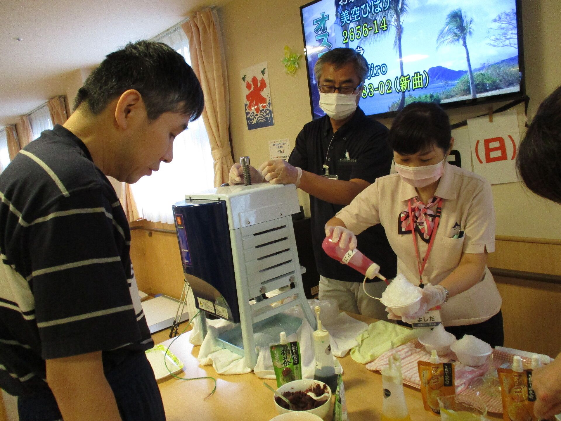 マスクと手袋をつけた女性が、かき氷を作っている様子
