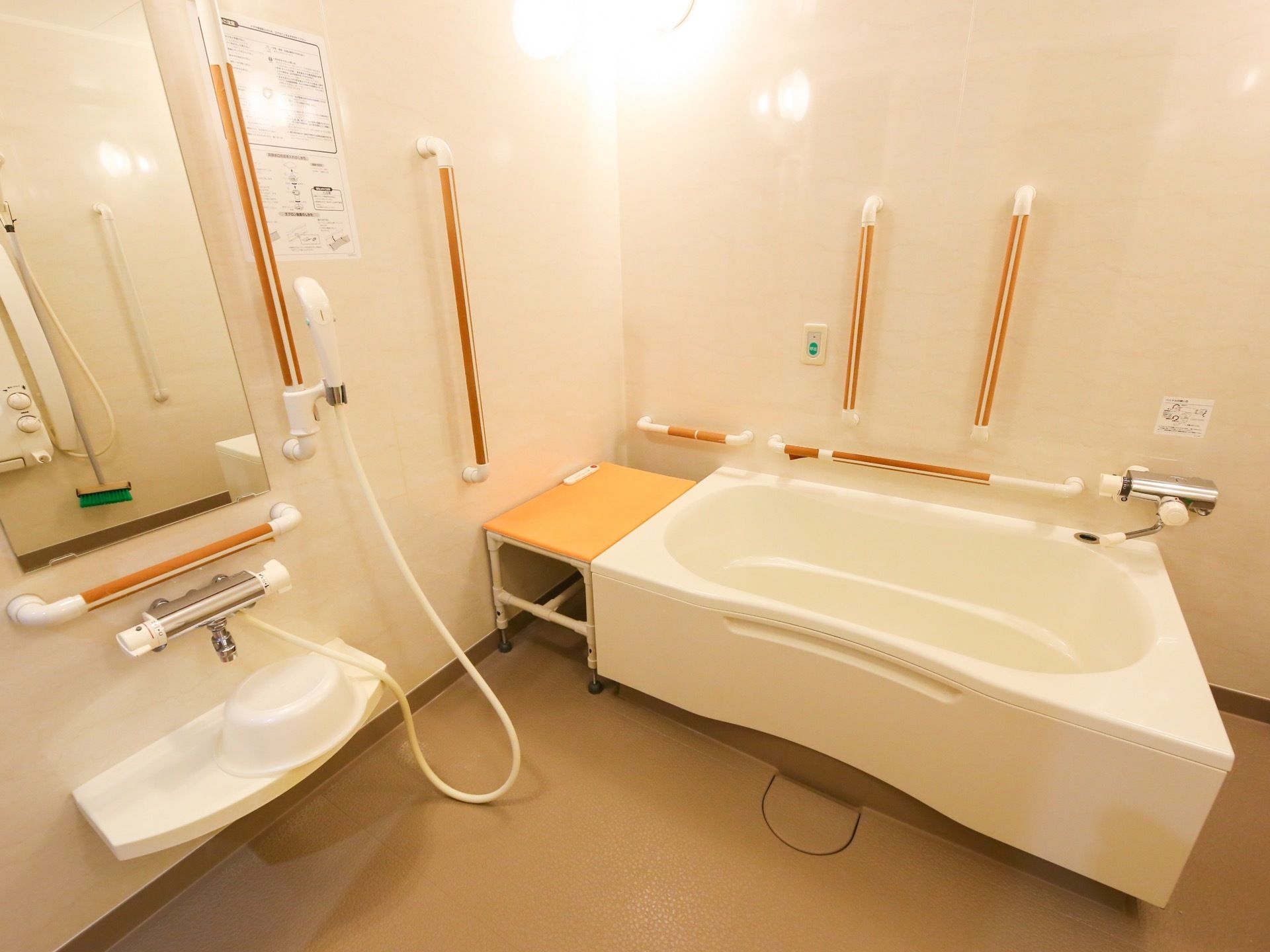 白を基調とした浴室である。洗い場には洗い桶が用意されている。壁にはいくつもの手すりが設置されている。
