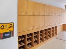 大きな靴箱の下半分はオープンタイプでスリッパが並べられ、上半分には扉が付き、そばにAEDもある。