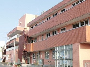 赤茶色の壁が印象的な鉄骨造の建物。高齢者向け施設「つくしんぼ弐番館」の外観