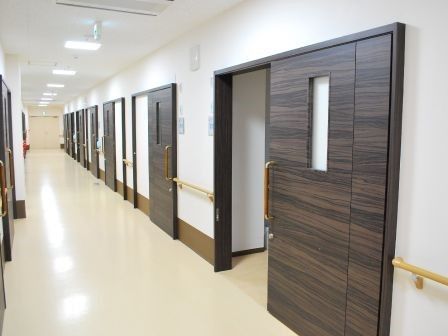 ダークブラウンの引き戸が設置された居室が並ぶ廊下。