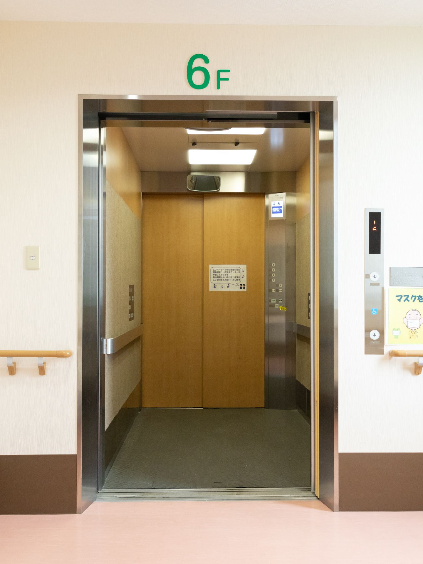 白い壁に配置された扉があいたエレベーター