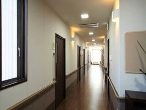 まっすぐに続く廊下と手摺が付いている壁。両側に個室が並んでいる