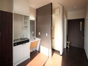 部屋の中にあるキッチンと洗面台を写した写真。奥のほうに出入り口が写っている