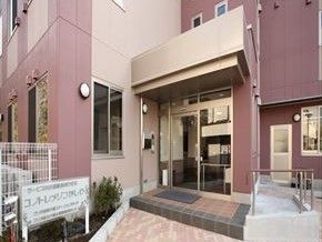 ピンク色のような淡い色合いの建物とその入り口。オールバリアフリーの環境