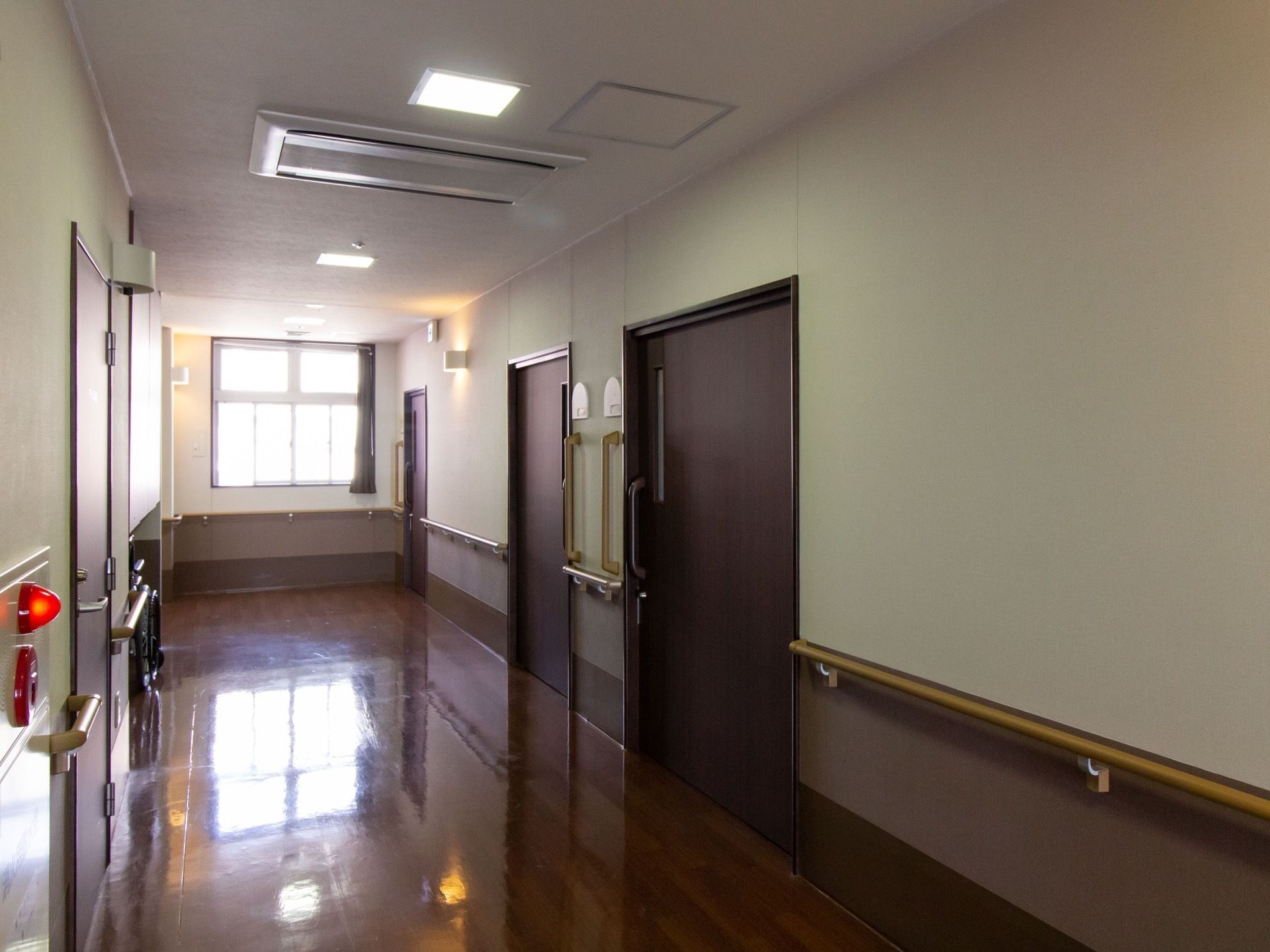 廊下の天井に埋め込み式の大型エアコンが設置されている。居室入口の横には、縦方向の大きな手すりがある。