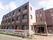 薄い紫色を基調とした３階建ての施設である。道路に面したフェンスに、施設名称や見学受付中と書かれた横断幕が掲げられている。