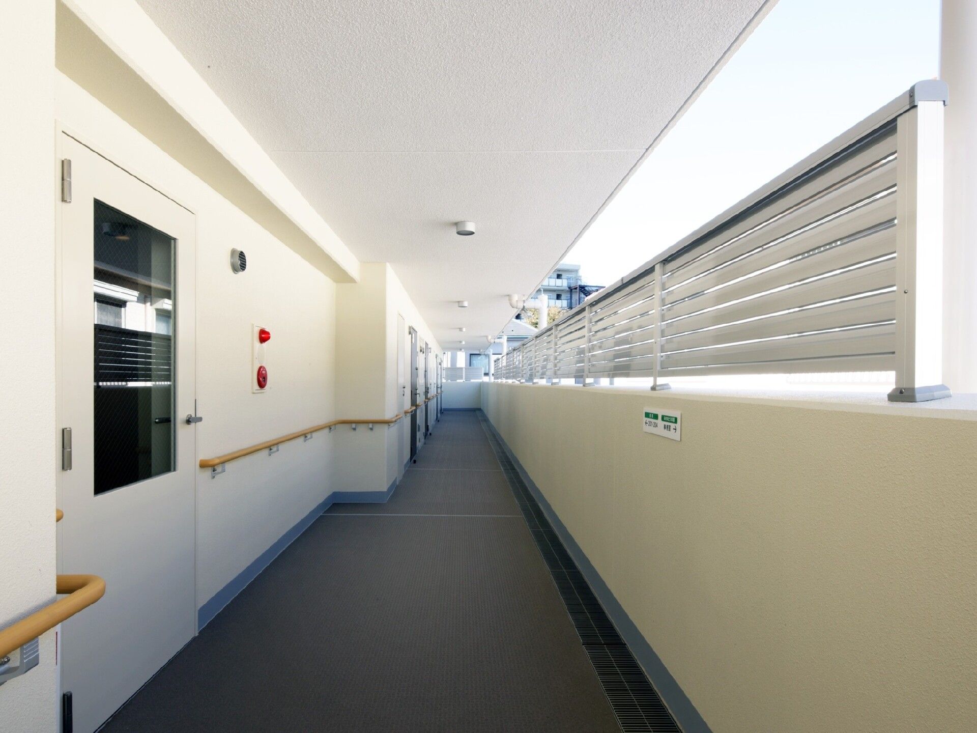 手すり付きの通路には防災設備が設置され、外側の壁には目隠しも付いている。