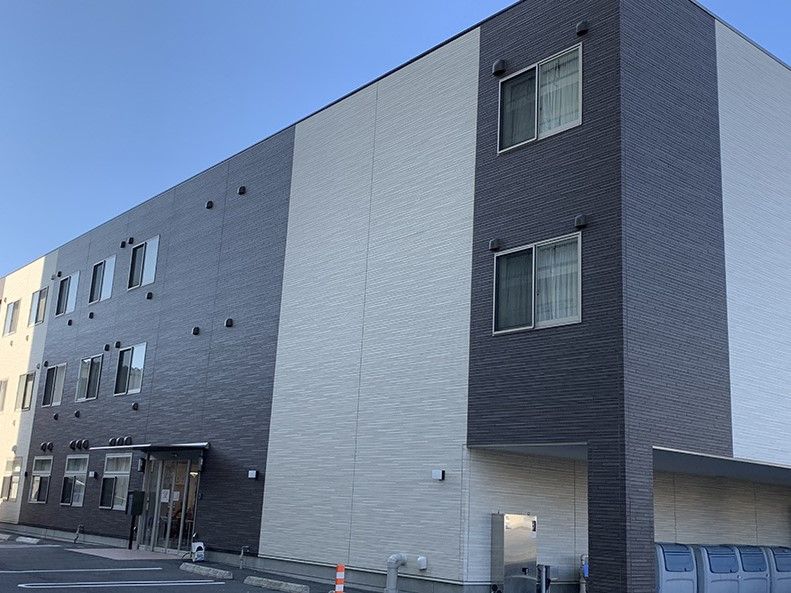 グレーとベージュの外壁の3階建て建築物