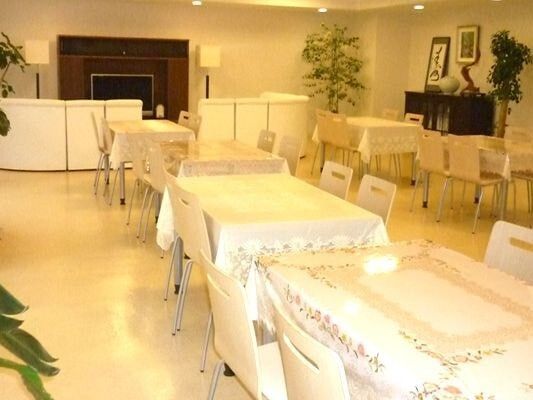 観葉植物がたくさん置かれた食堂にはテーブルクロスがセットされたダイニングテーブルが複数置かれている。