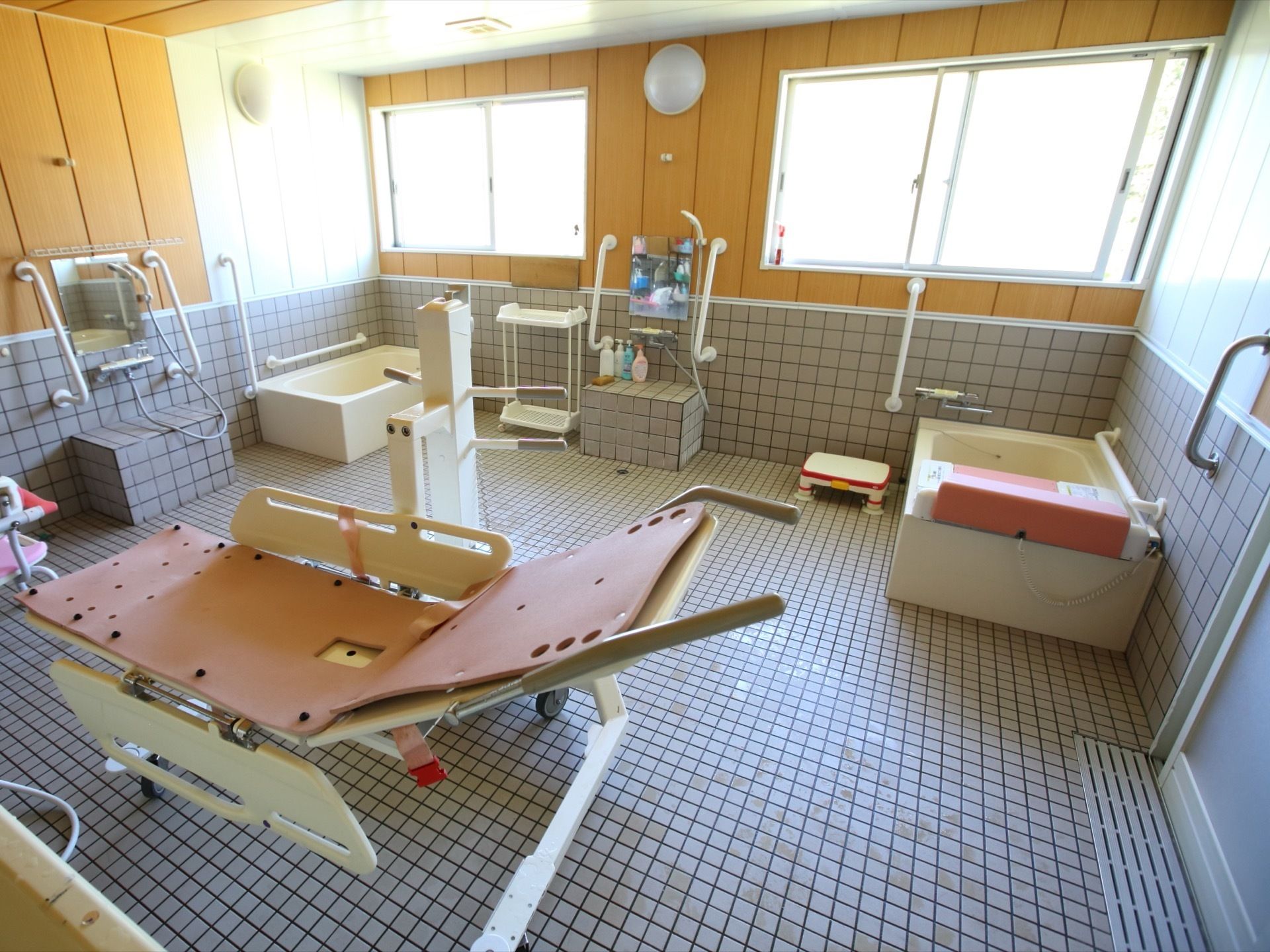 浴室には、窓が2箇所に設置されている。個浴槽が両サイドの壁際に完備され、介護入浴機器が置かれている。