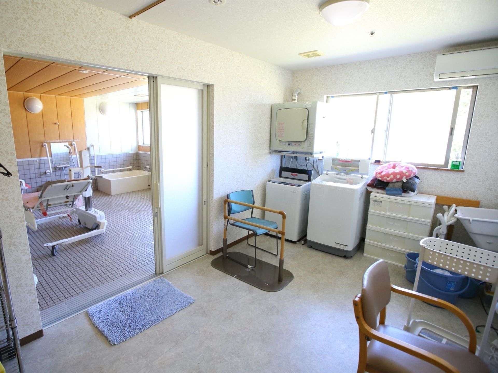 介護用の機器を備えた浴室と洗濯機のある脱衣場