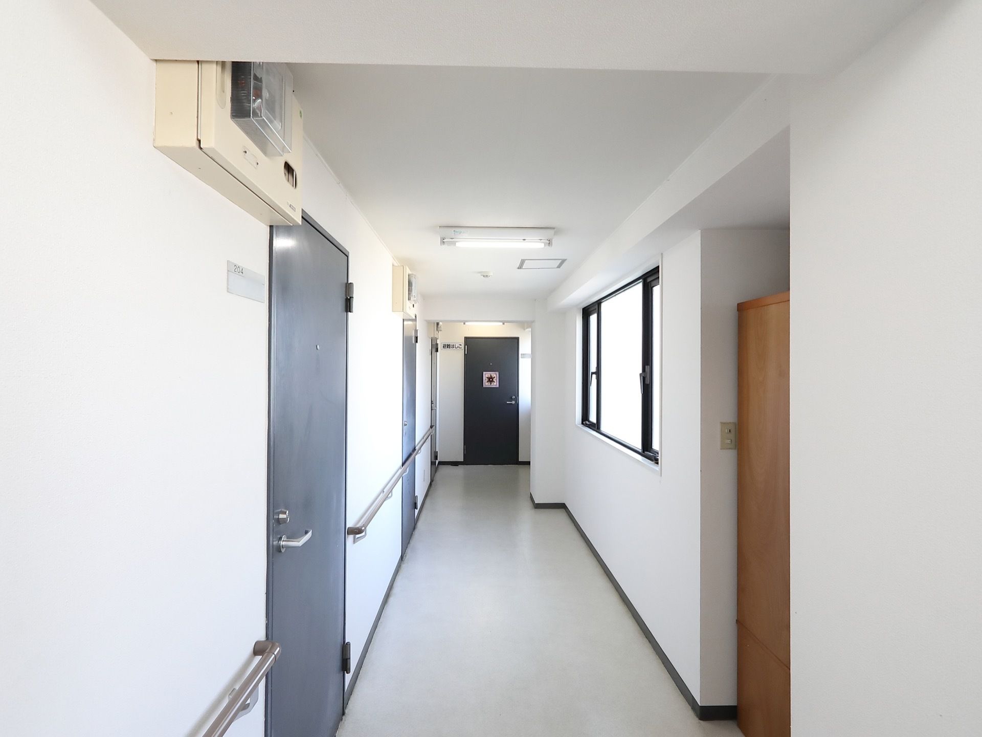 真っ白な壁に居室のドアは黒く、一般的なアパートのような見た目である。壁には手すりがついているため、歩きやすい。
