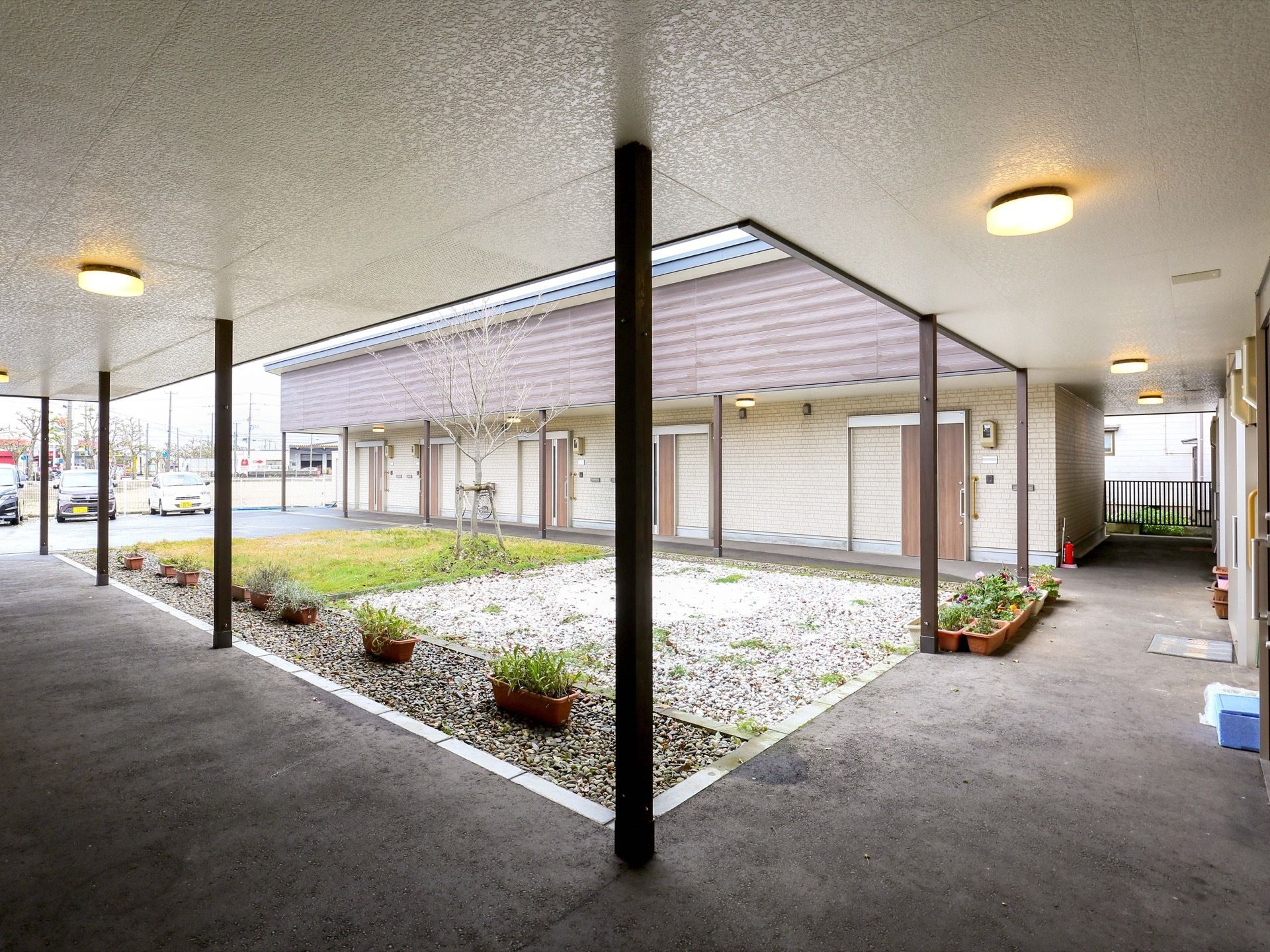 コの字型の建物に沿って設けられた外廊下である。大きなひさしが付いており、照明が天井に取り付けられている。