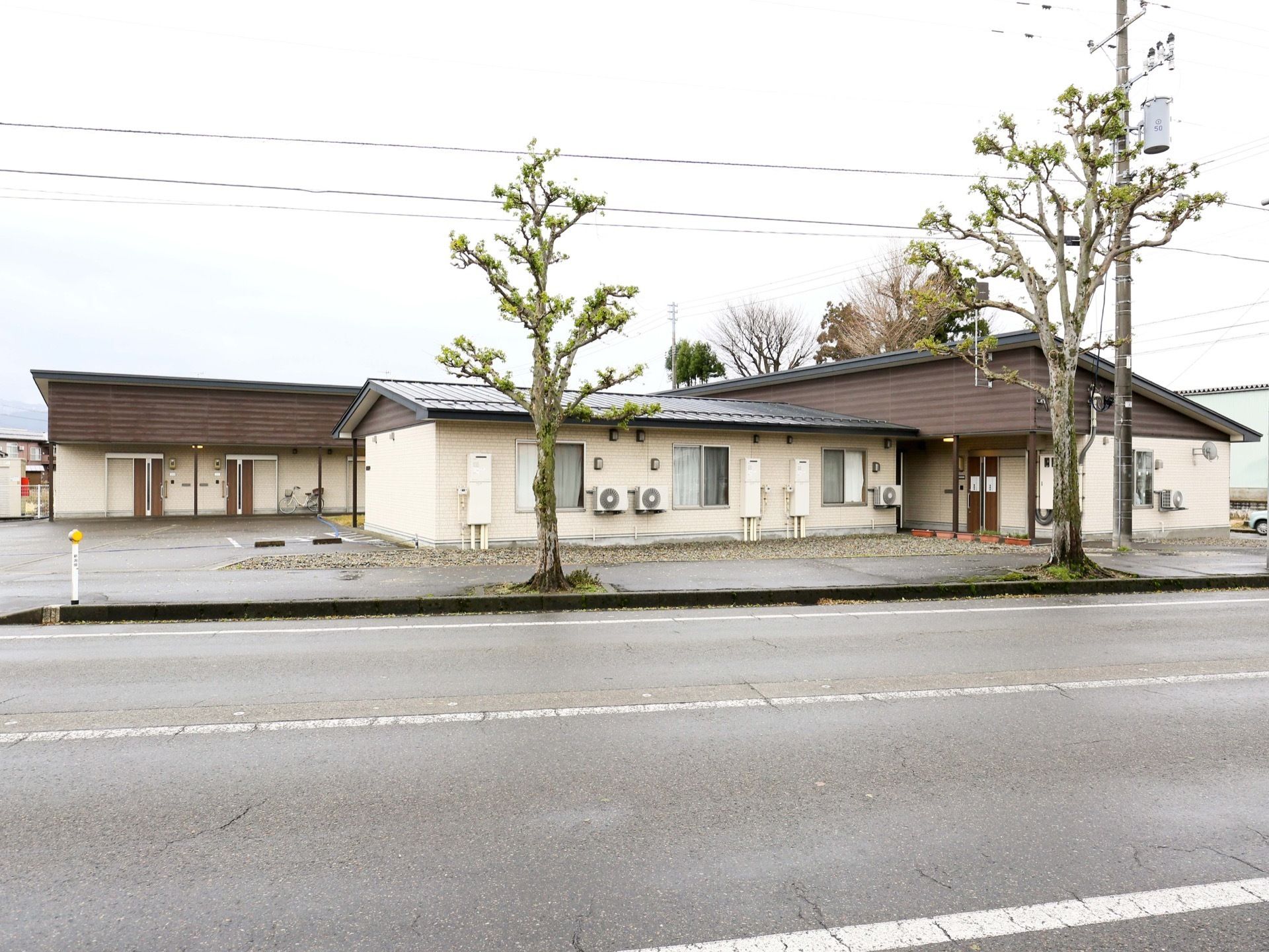 茶色い屋根の平屋建ての施設である。敷地内に駐車スペースが設けられており、側の歩道には街路樹が植えられている。