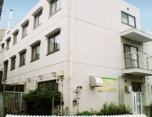 3階建ての白い建物と緑豊かな庭
