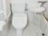 右側には一人用の浴槽が設置され、左側には手すり付きのトイレがあり、いずれも白でまとめられている。