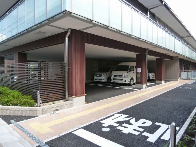 大きく「止まれ」と書かれた道路の横には点字ブロックが敷かれた歩道があり、住宅の建物が建っている。