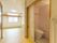 ピンクの壁紙が貼られたトイレは手すりが付いていて、フローリングの居室内には段差がない。窓にはカーテンがなく、天井には照明がある。