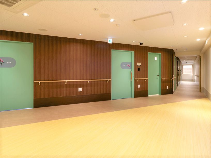 右側にはまっすぐな廊下が続いていて、正面には幅の広いスライド式のドアが３つ並んでいる。フロアはベージュで壁はブラウン、手すりは木製。