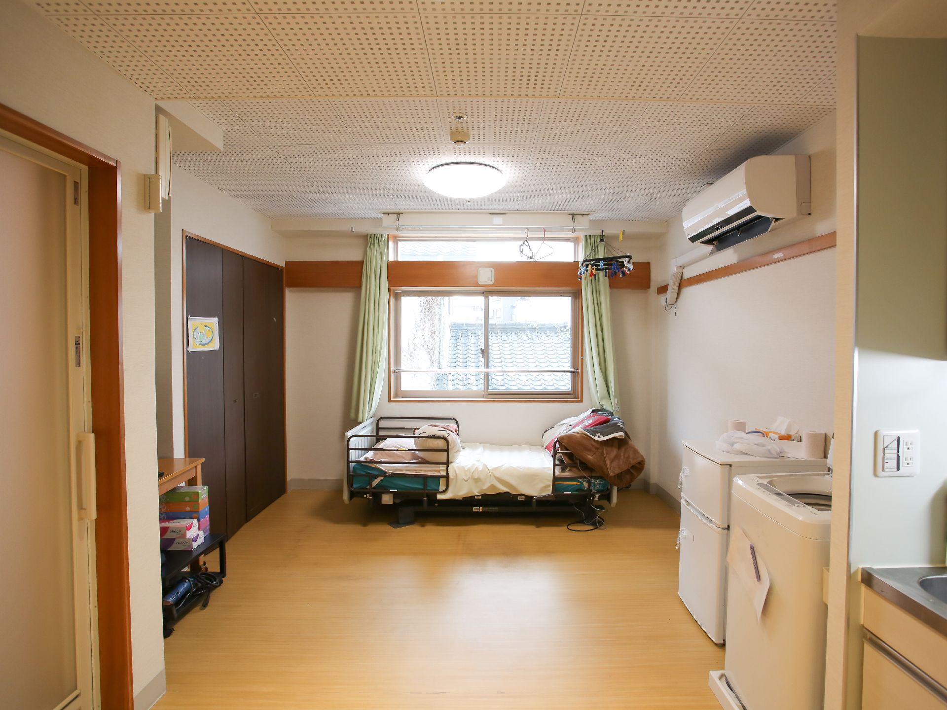 青い椅子とテーブル、ベッドが設置された居室